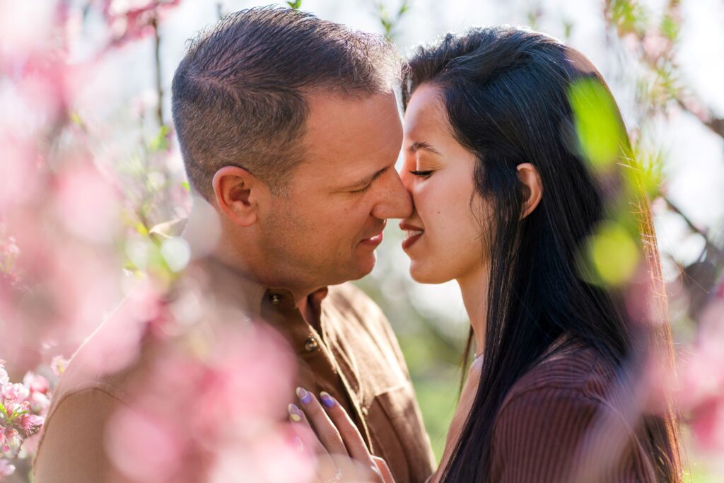 Couple kissing in a peach blossom orchard in Charlotte NC