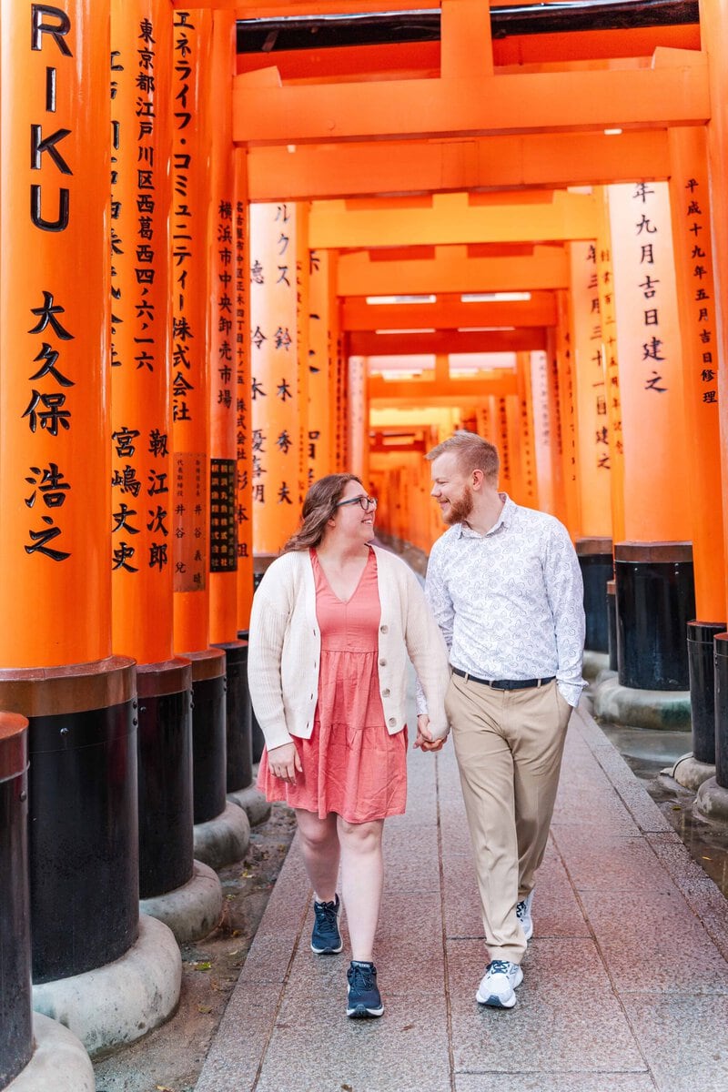 Japan photoshoot at Fushimi Inari Shrine with Cam and Maura. The couples walks underneath the bright orange Torii gates