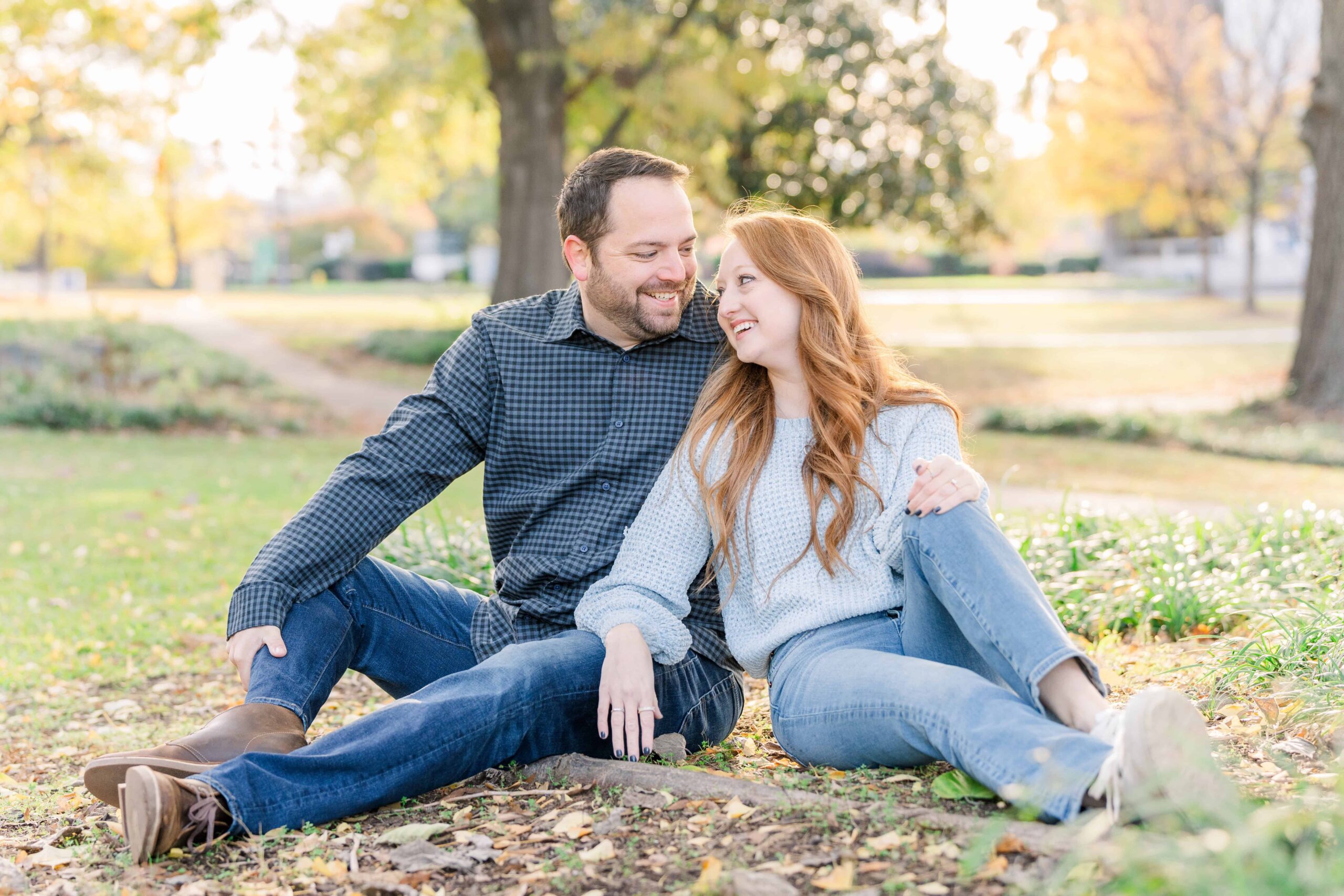 Caroline and Derek sit underneath the big, yellow, gingko tree in Marshall Park. It's fall and the vibrant colors surround them while they laugh at each other.