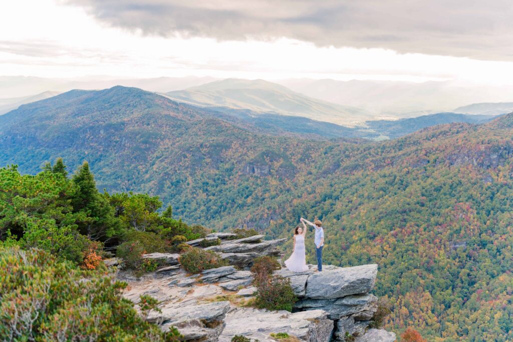 Smiling couple during a Blue Ridge Mountain engagement session, framed by golden light and panoramic ridgeline views.