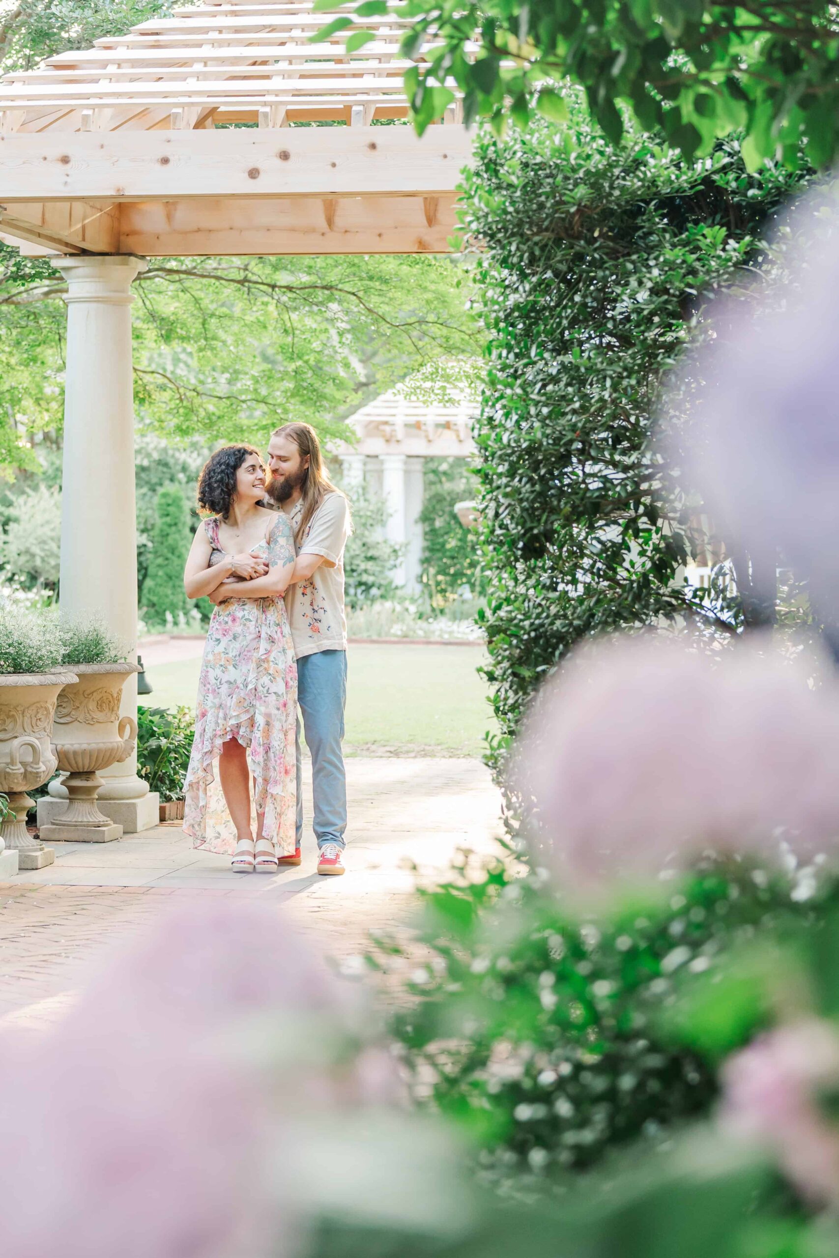 Engaged couple posing in the White Garden at Daniel Stowe Conservancy with blooming hydrangeas