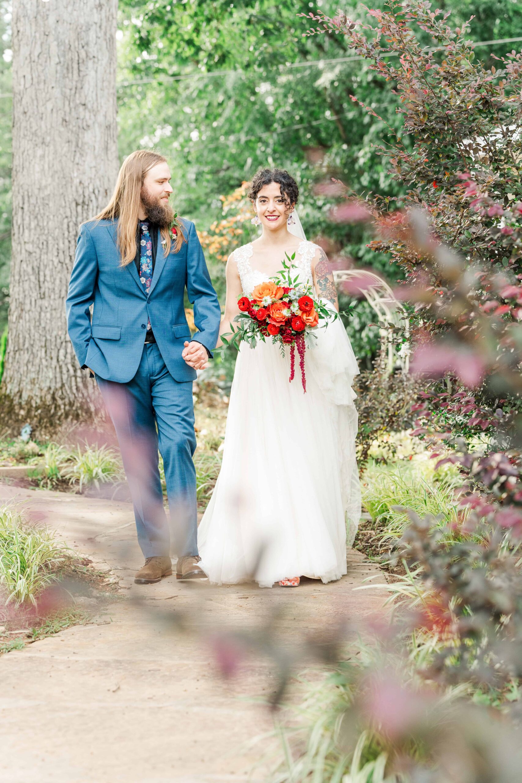 Couple walking through the greenery at Mariposa Chapel wedding venue in Iron Station, NC
