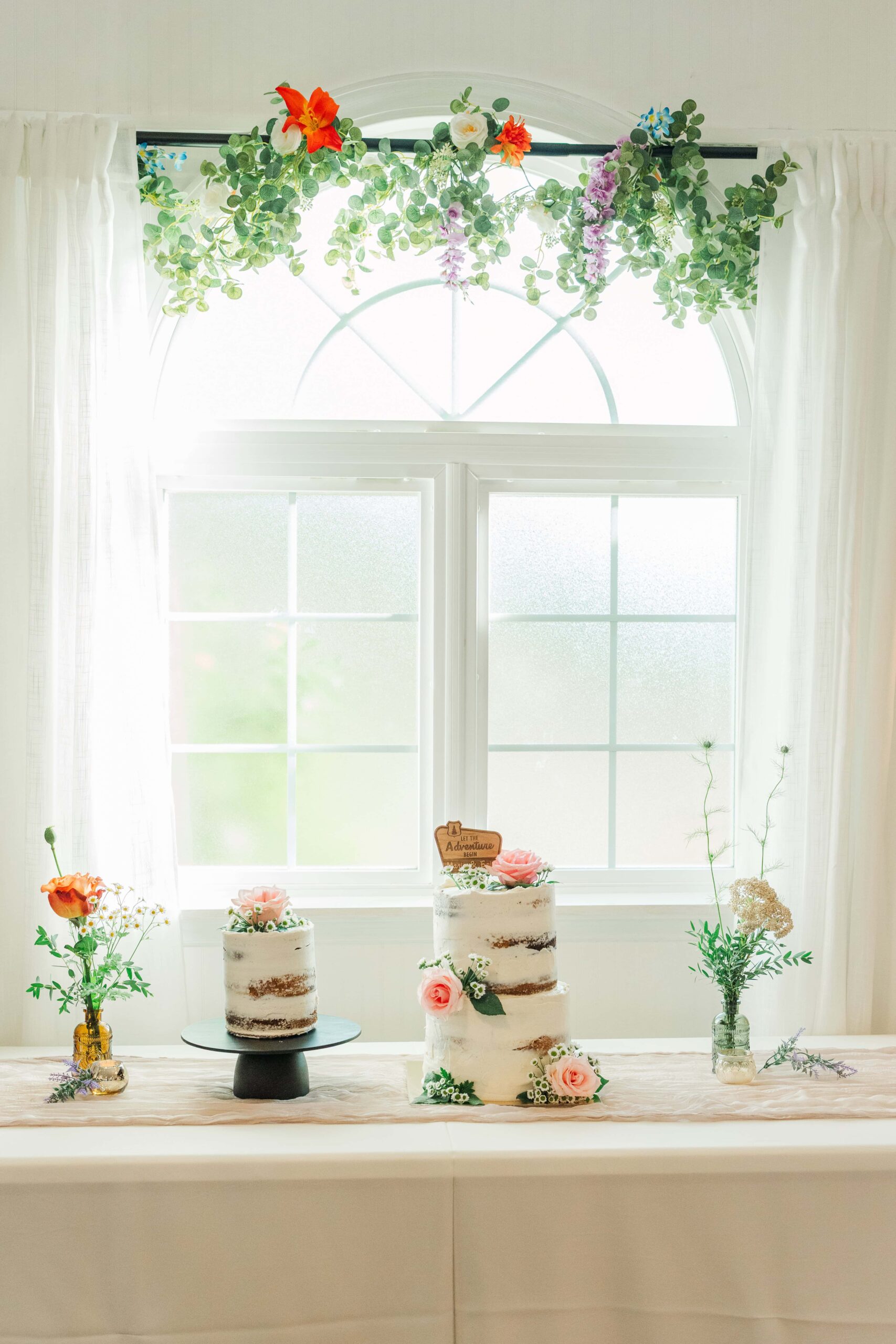 Wedding cake and florals displayed in indoor reception hall at Mariposa Chapel