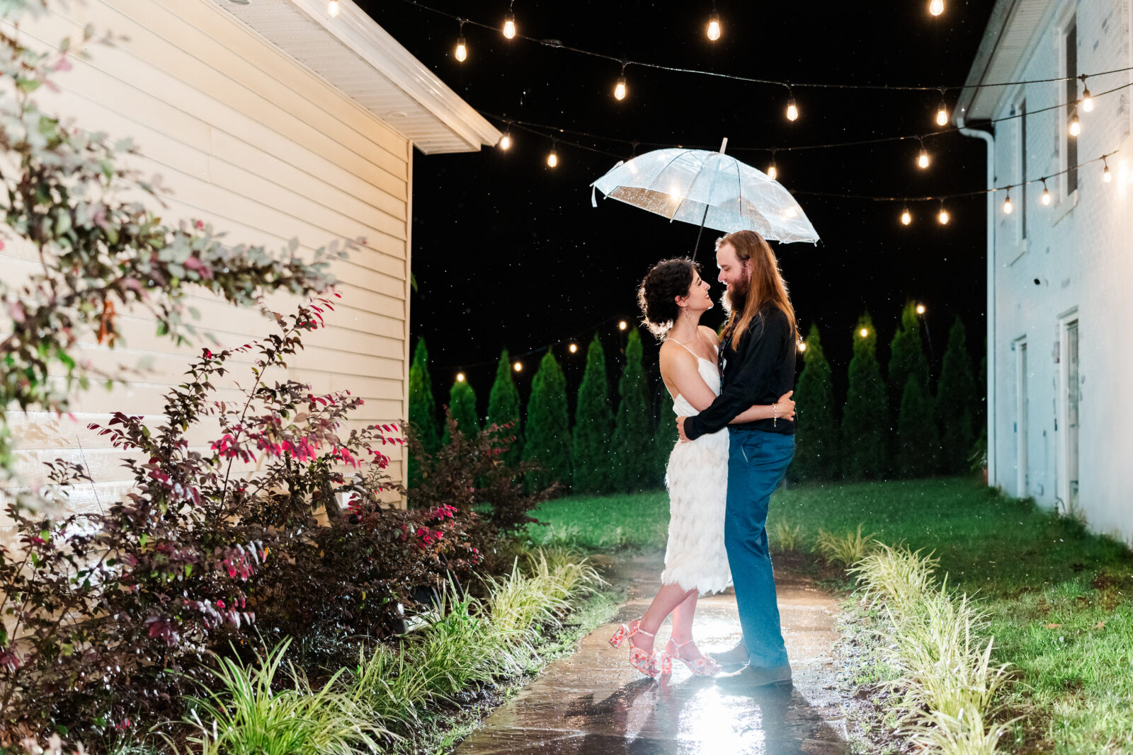 couple posing in the rain under twinkle lights on their wedding day. Make sure to prioritize photography in your wedding budget to capture images like this