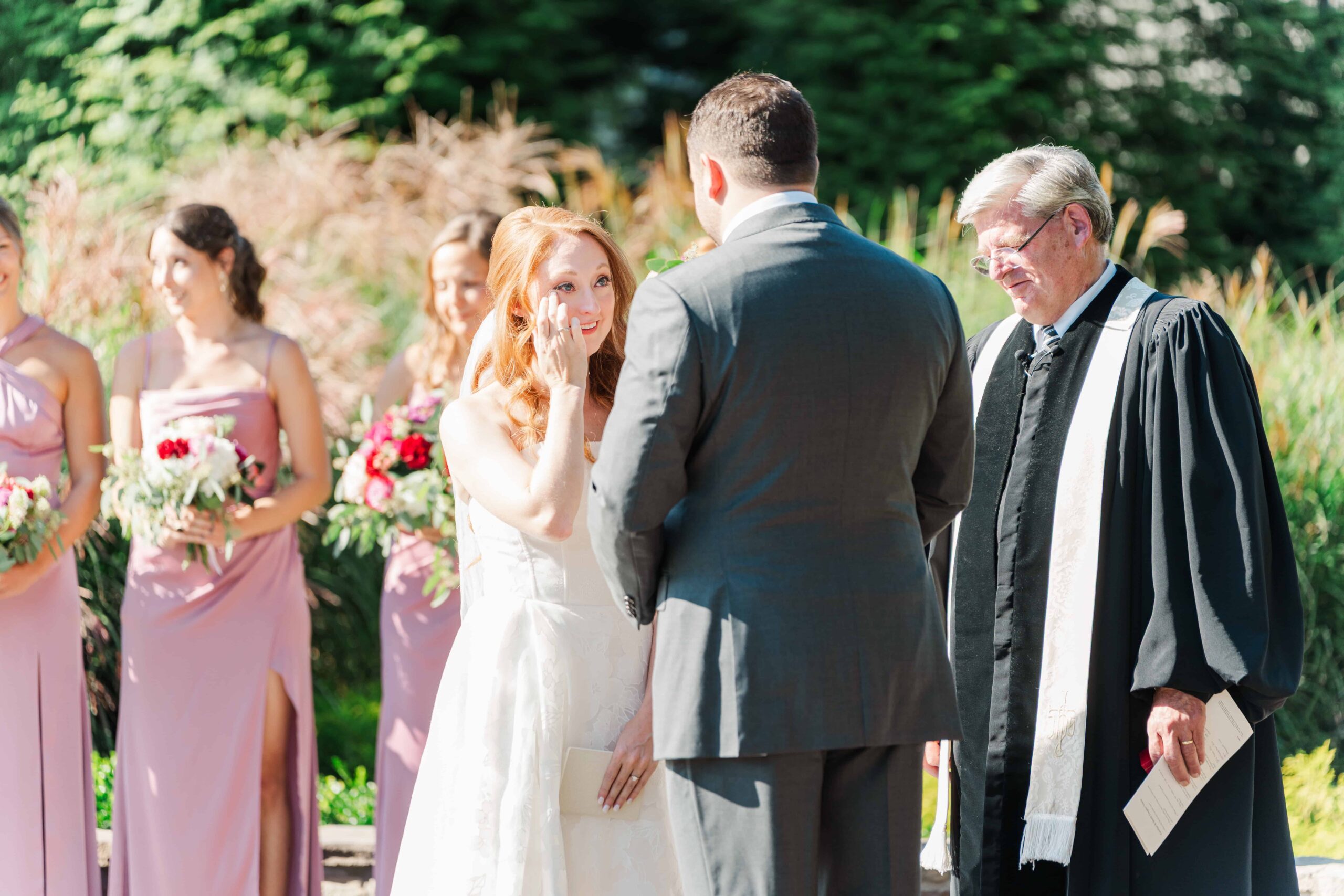 Bride wiping joyful tear during wedding ceremony
