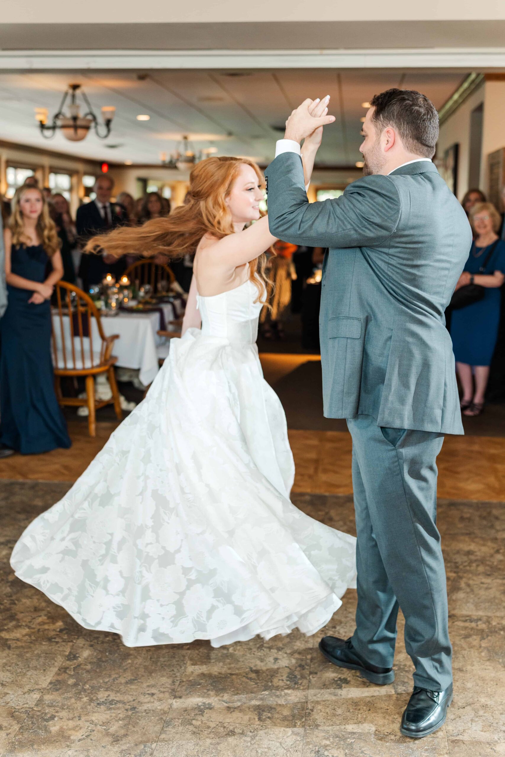 Groom spinning bride on dance floor at grand reception