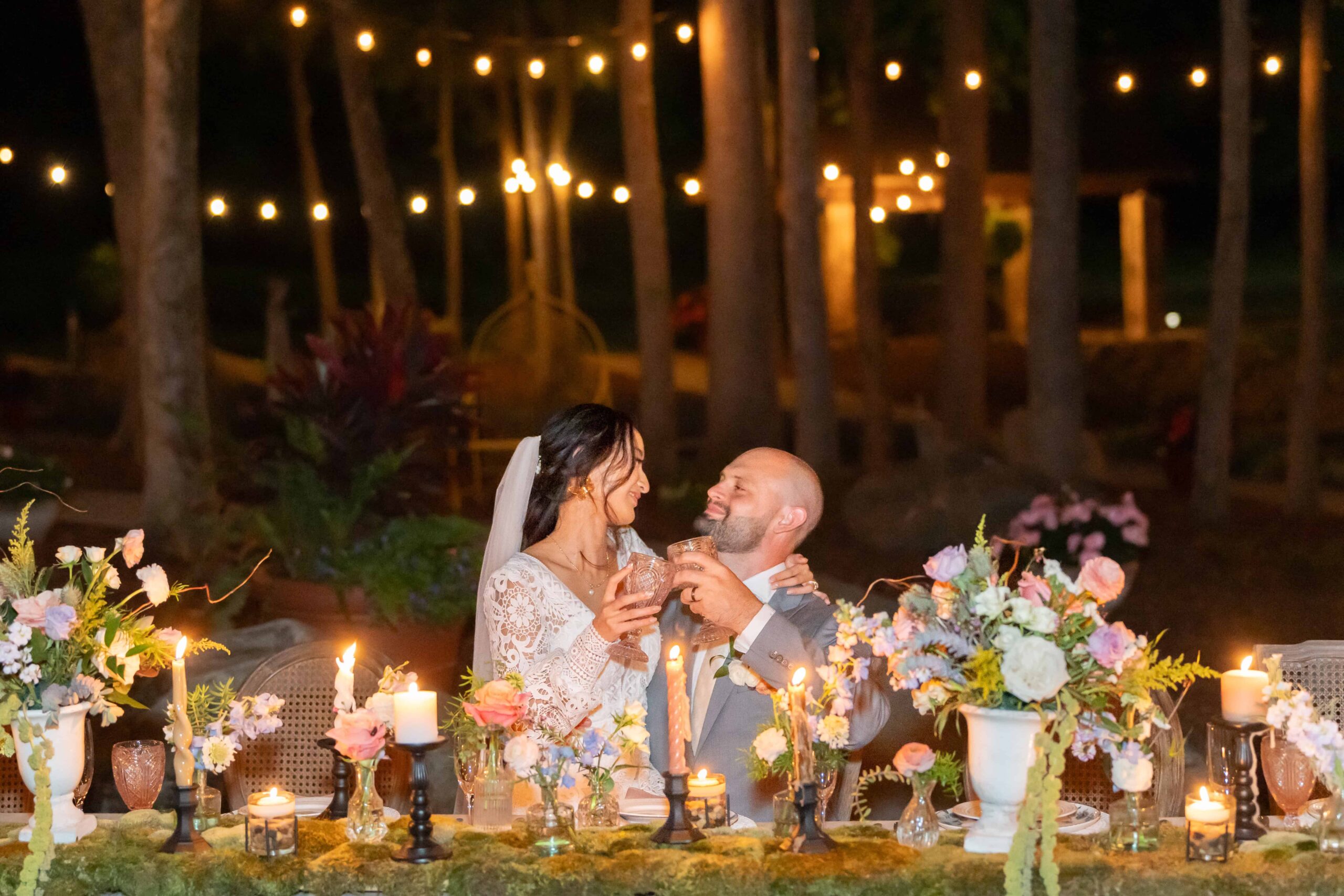 bride and groom toasting by candlelight in the garden. Make sure to prioritize photography in your wedding budget to capture images like this