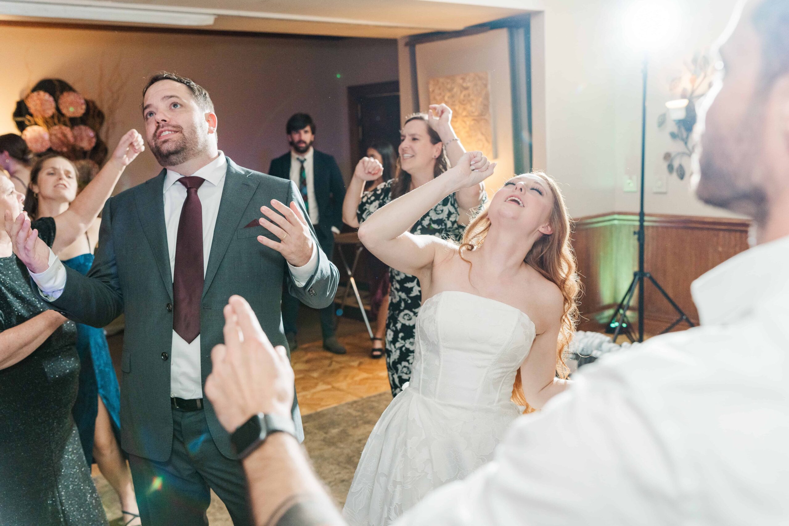 Bride and groom laughing with wedding party on dance floor