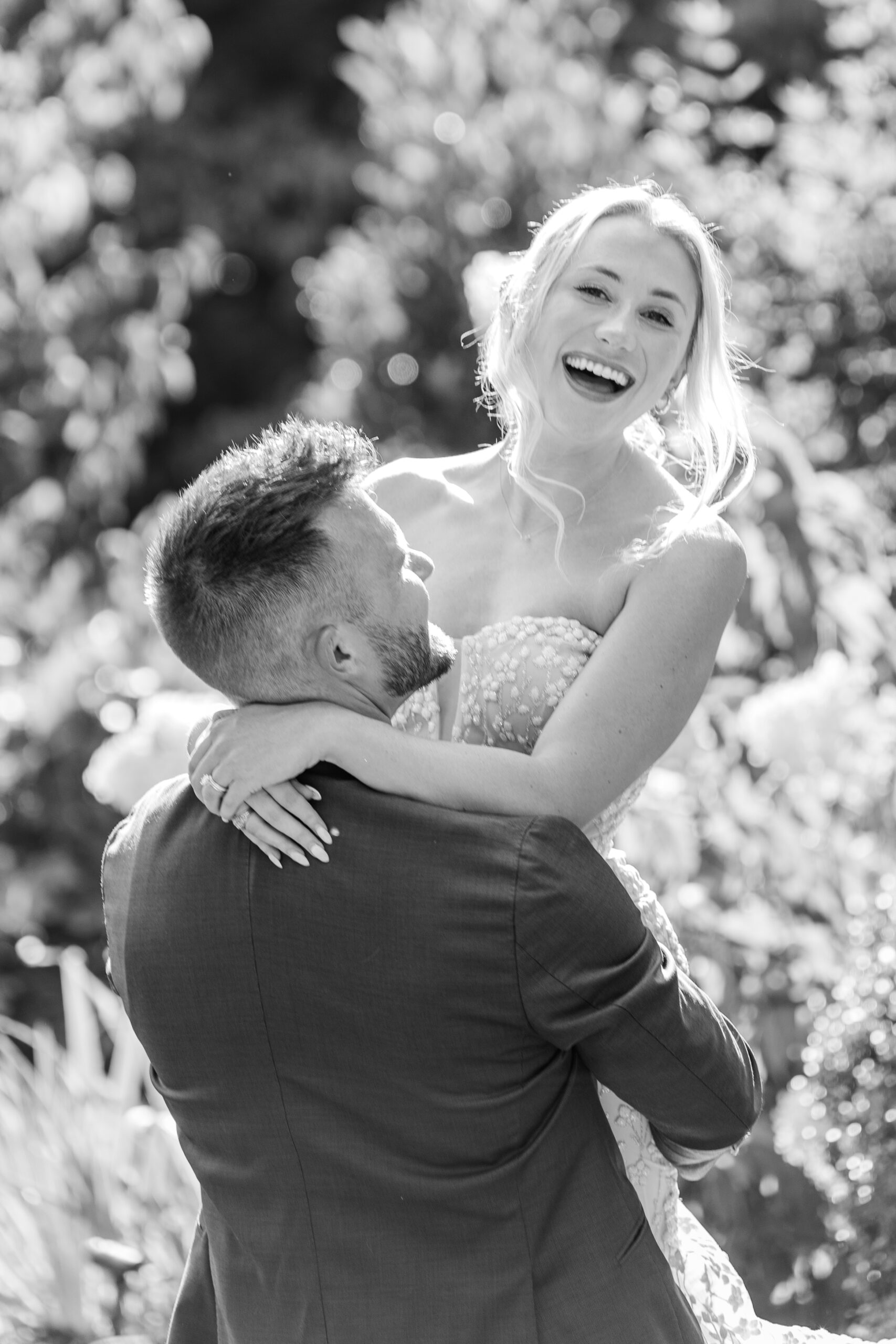 Bride laughs while groom holds her and spins. emotional moments like this captured when you prioritize photography in your wedding budget