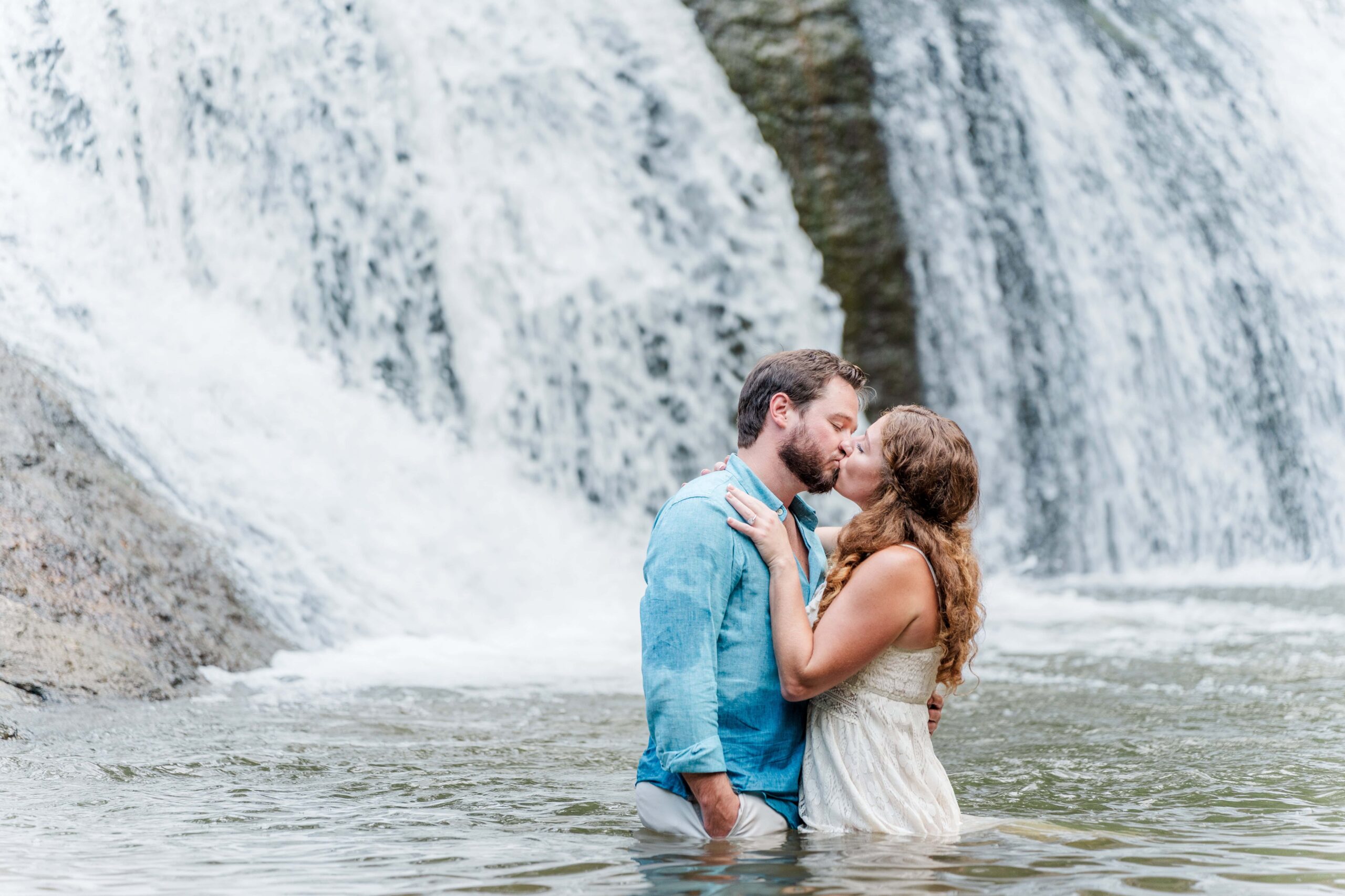 Couple under McGalliard Falls waterfall during summer outdoor engagement session