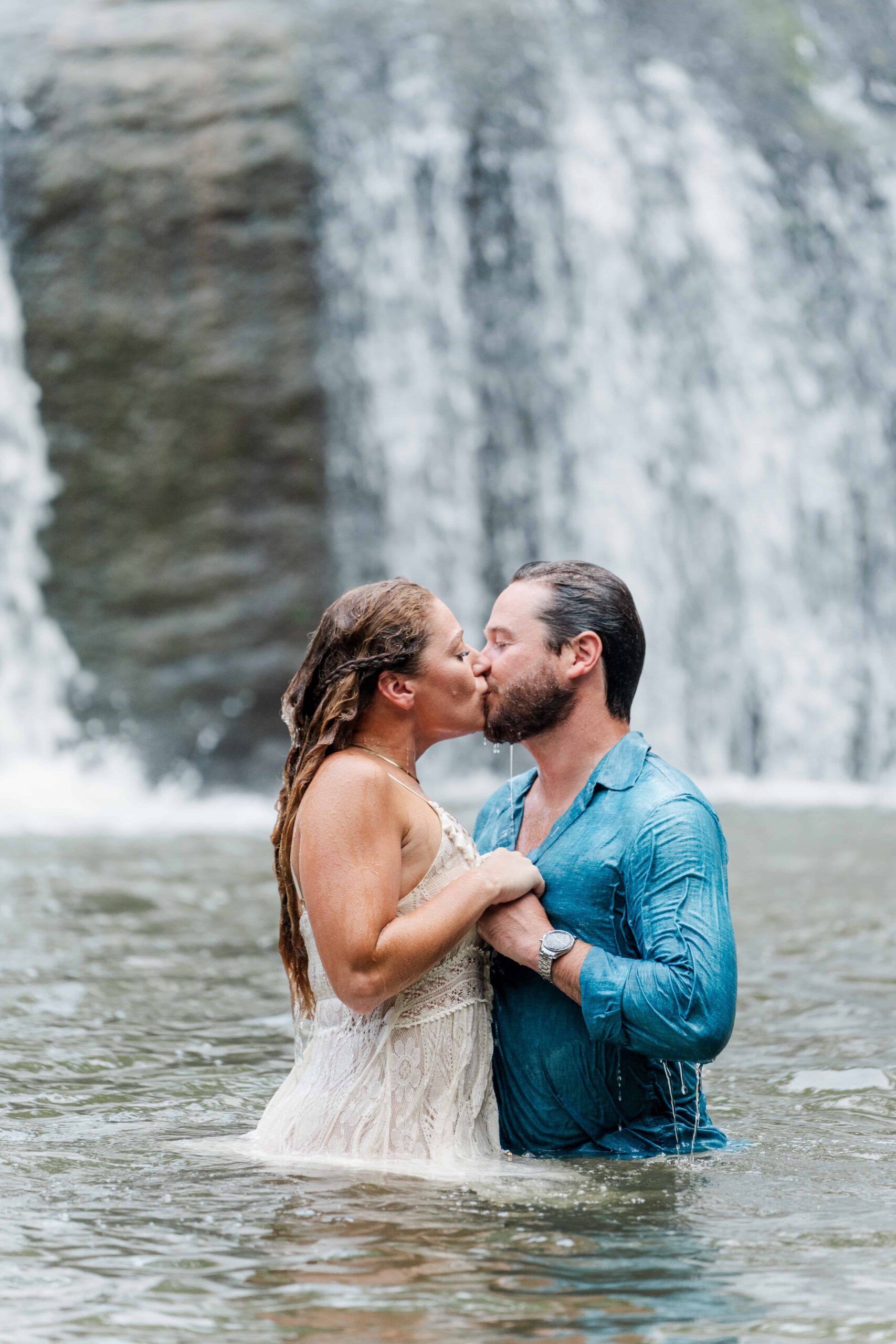 Couple kissing under the waterfall at McGalliard Falls engagement session
