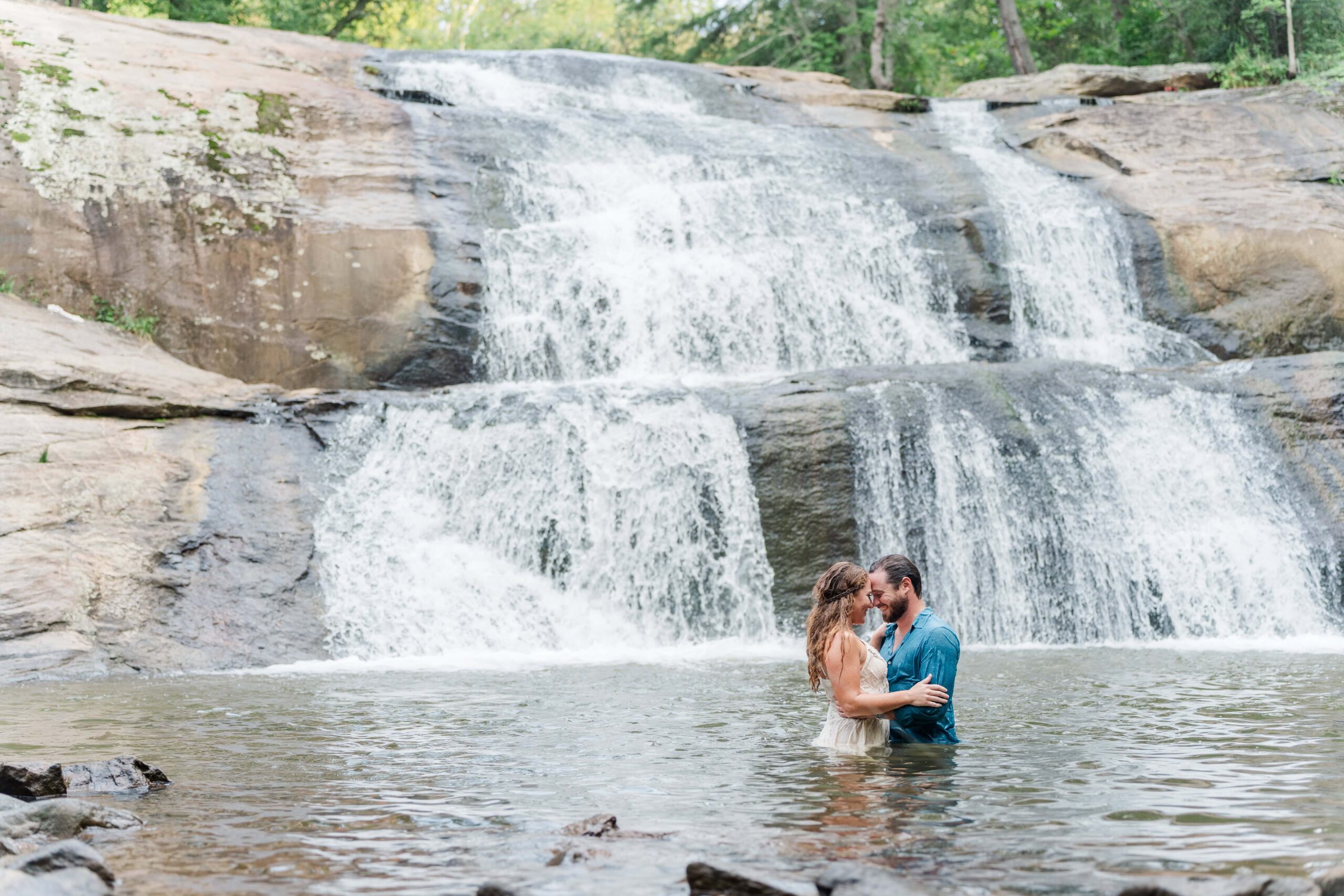 Adventure couple sharing a romantic moment during waterfall engagement session in NC