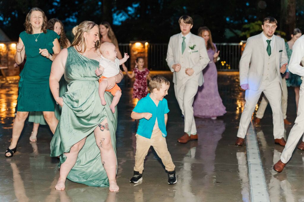 Guests dancing in the rain on the outdoor patio dancefloor during a heron hill venue wedding