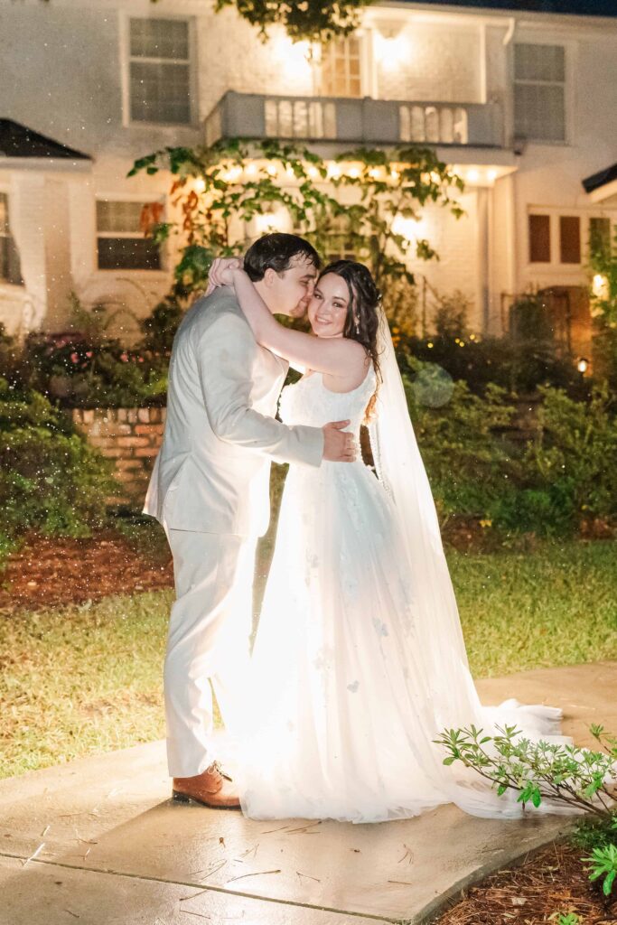Night romantic portraits of the bride and groom in the rain with house lights behind them at heron hill venue