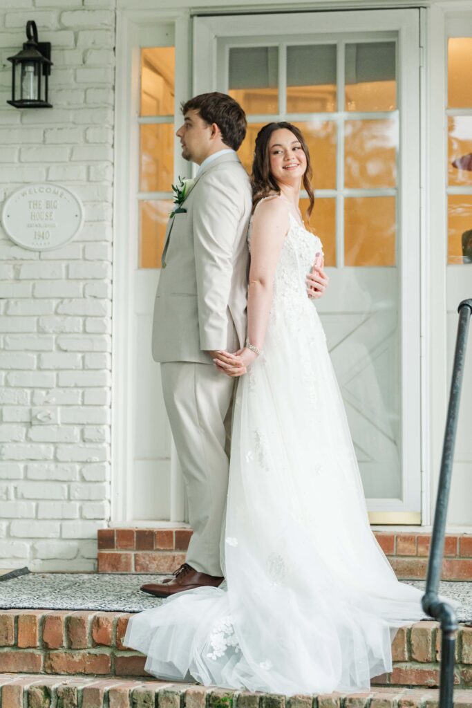 Bride and groom first touch under Heron Hill Venue's covered side porch