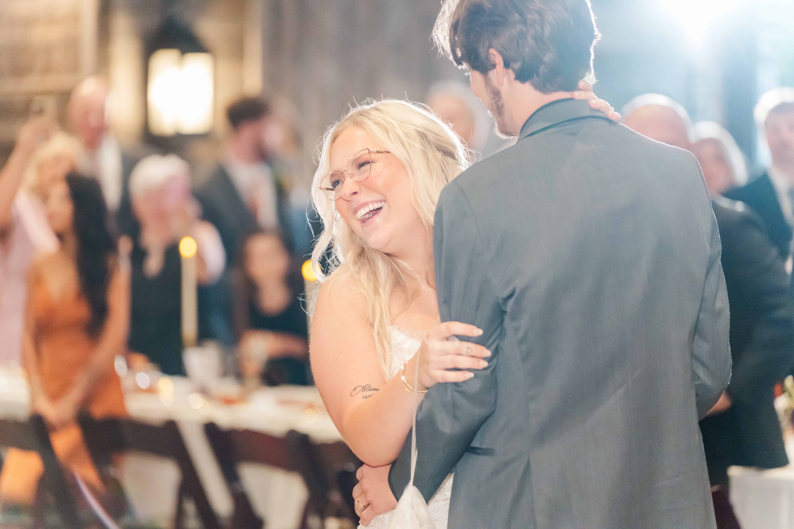 The married couple laughing during their first dance by the stone fireplace
