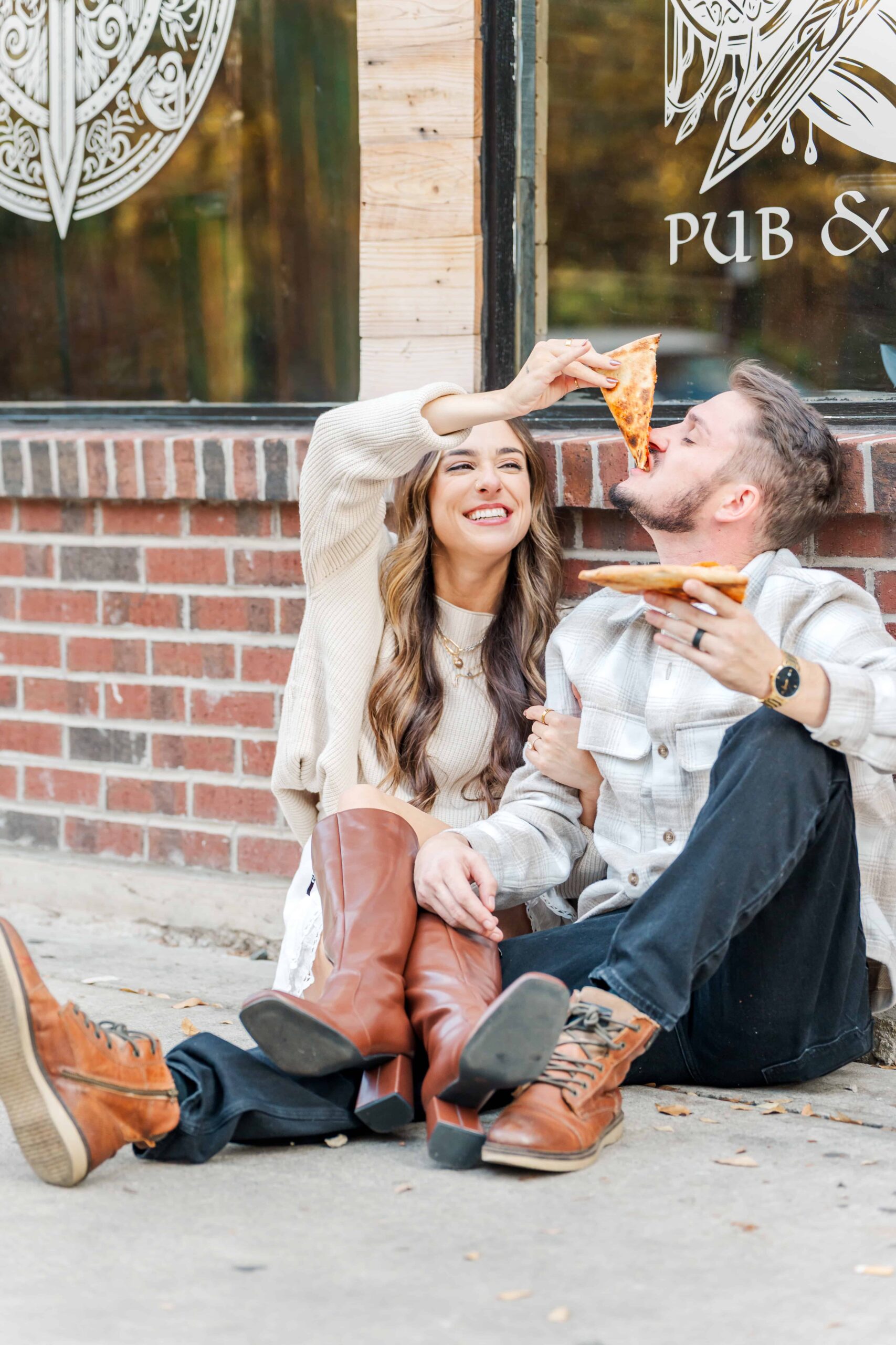 Couple laughing together while eating pizza in uptown Charlotte alley