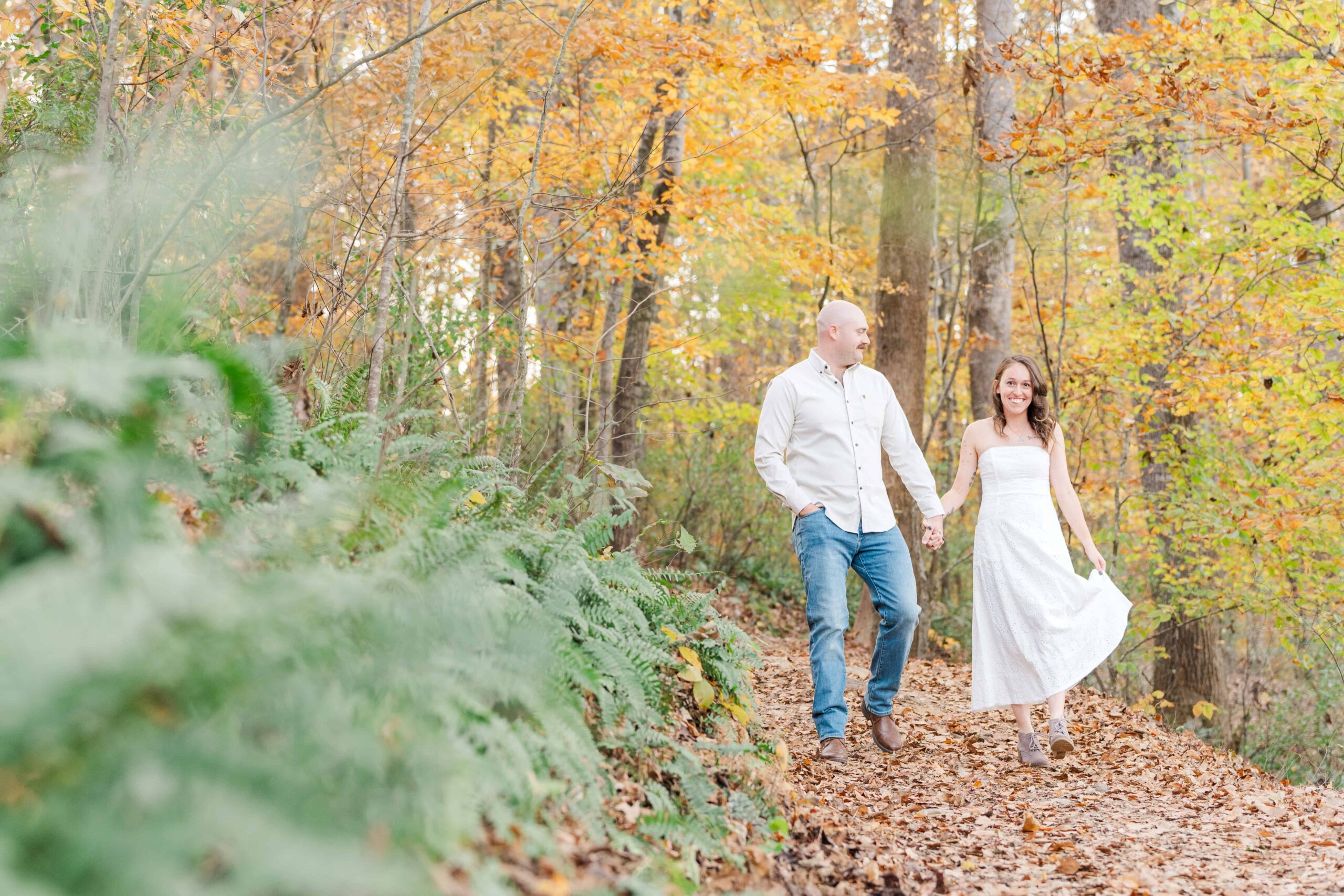 Couple walking along dirt trail during outdoor engagement session
