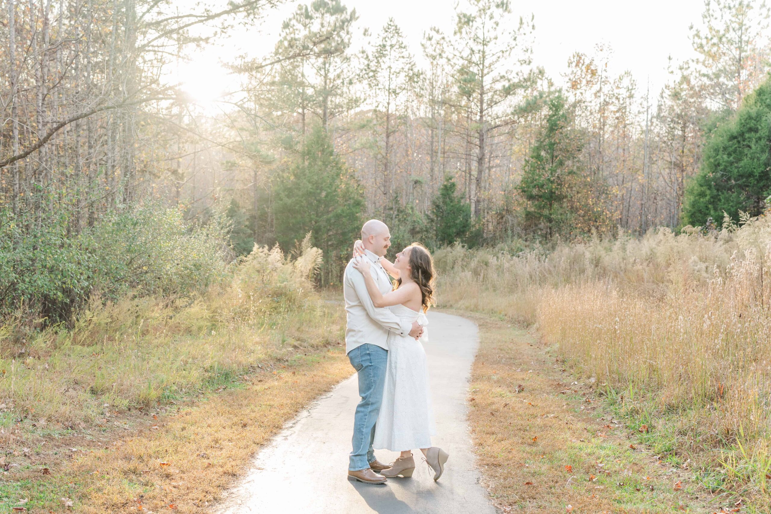 Charlotte engagement photos in front of tall trees during golden hour