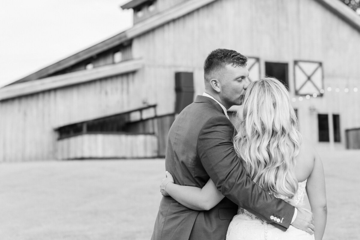 Couple posing outside the stunning indoor event barn at Camelot Meadows
