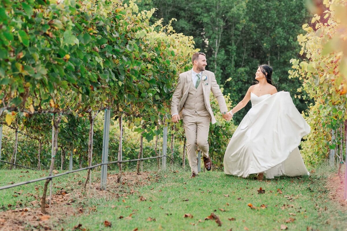 Bride and groom running through the vineyard at Dugaren Vineyards Wedding